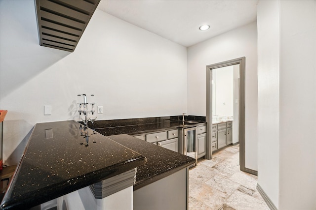 22009 Holly Creek Trl, Tomball, TX 77377 - kitchen with baseboards, recessed lighting, a peninsula, dark stone counters, and beverage cooler