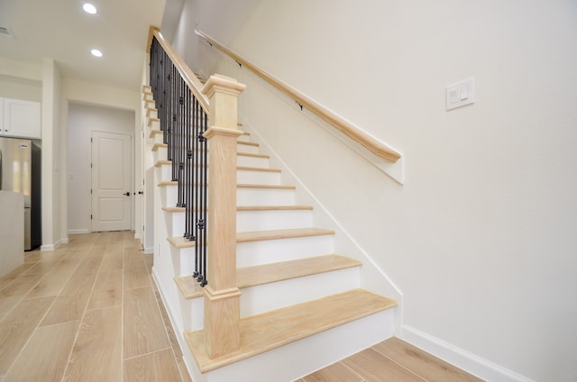 stairway featuring recessed lighting, wood finished floors, and baseboards