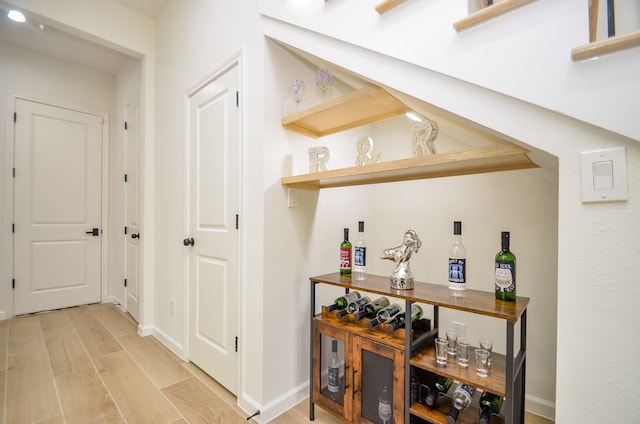 indoor dry bar with light wood-type flooring and baseboards