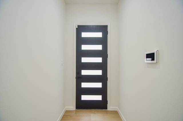 doorway to outside with light wood-type flooring and baseboards