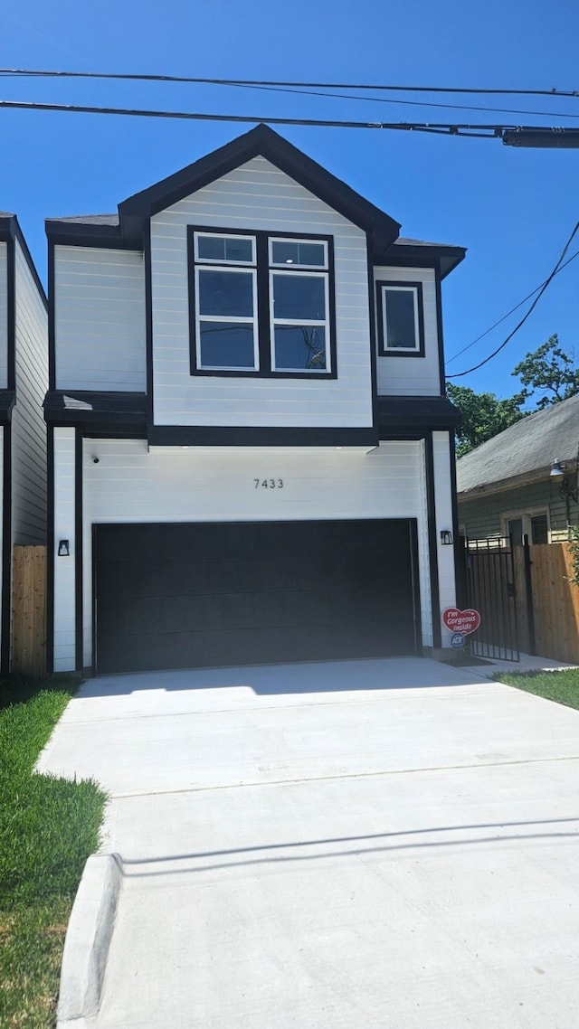 view of front facade featuring a garage, fence, and concrete driveway