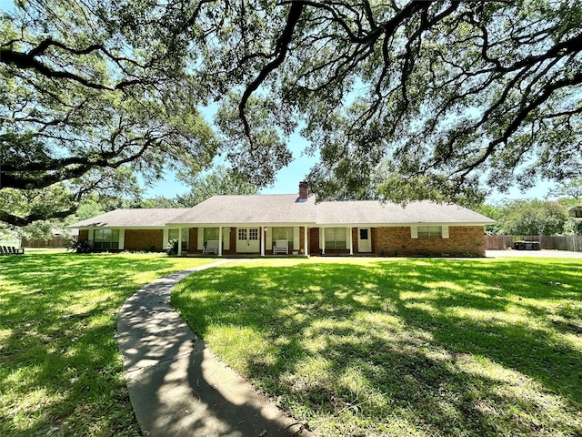 ranch-style house featuring a chimney, a front yard, and fence