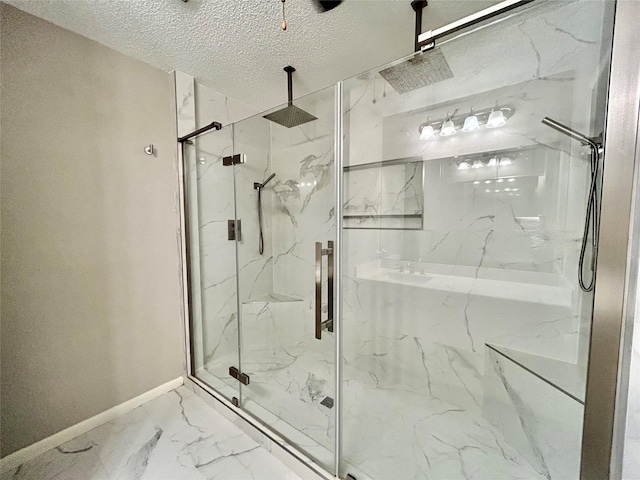 full bath with a marble finish shower, baseboards, marble finish floor, and a textured ceiling