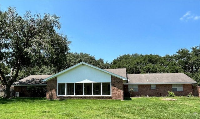 back of house with brick siding and a yard