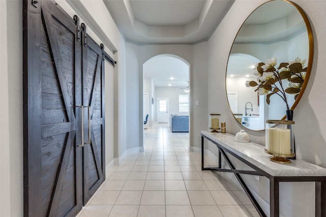 2411 Ocean Key Dr, La Marque, TX 77568 - hallway featuring baseboards, arched walkways, light tile patterned flooring, and a barn door