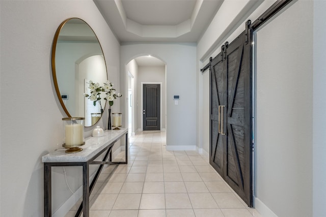 2411 Ocean Key Dr, La Marque, TX 77568 - hall featuring baseboards, arched walkways, a barn door, a tray ceiling, and light tile patterned flooring