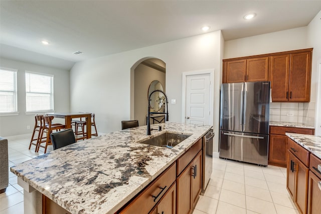 2411 Ocean Key Dr, La Marque, TX 77568 - kitchen with visible vents, arched walkways, a sink, stainless steel appliances, and light stone counters
