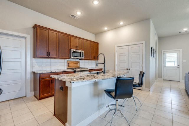 2411 Ocean Key Dr, La Marque, TX 77568 - kitchen with light tile patterned floors, appliances with stainless steel finishes, light stone counters, a sink, and decorative backsplash