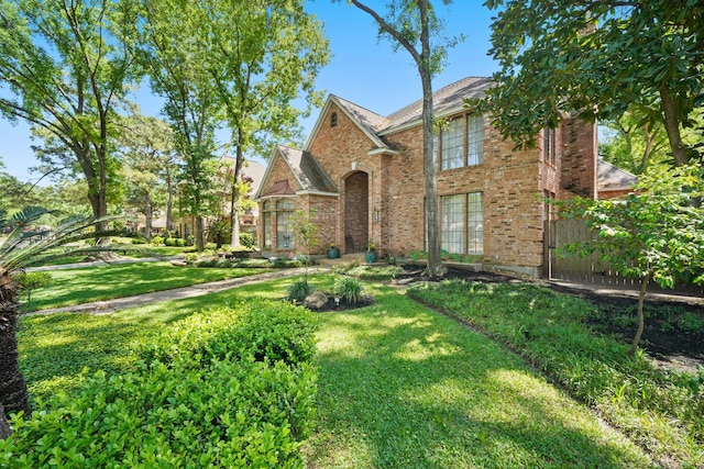 traditional-style house with brick siding, fence, and a front yard