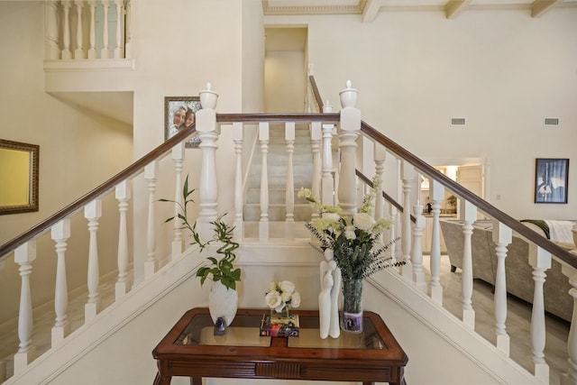 stairway featuring visible vents, a towering ceiling, and beam ceiling