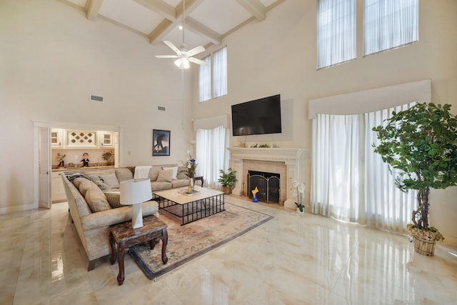 living area with a ceiling fan, beamed ceiling, a fireplace, a high ceiling, and visible vents