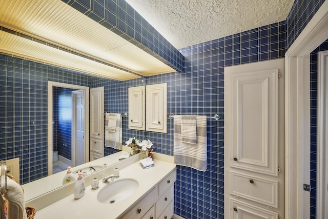 bathroom with vanity, a textured ceiling, and tile walls