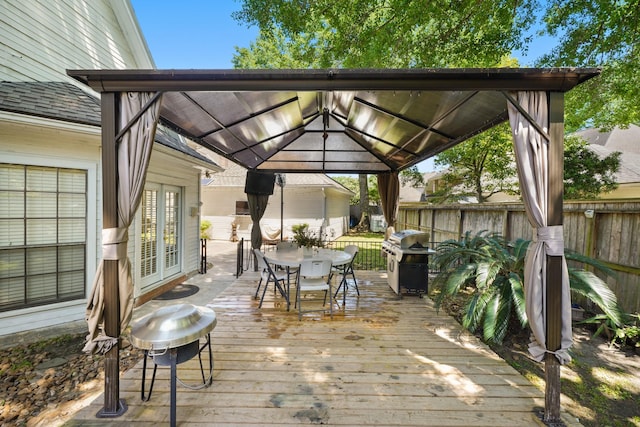 deck with french doors, a grill, a gazebo, fence, and outdoor dining area