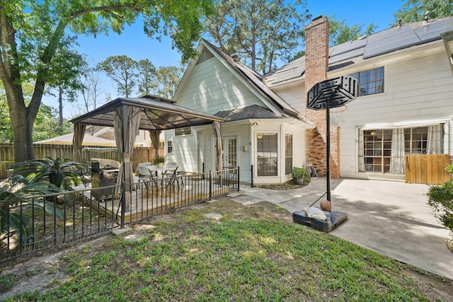 back of house featuring a gazebo, a fenced backyard, a patio, and a chimney