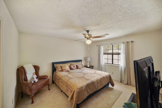 bedroom featuring light carpet, a ceiling fan, visible vents, and a textured ceiling
