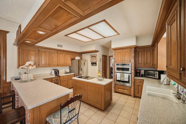 kitchen featuring light countertops, a sink, light tile patterned floors, a kitchen bar, and appliances with stainless steel finishes