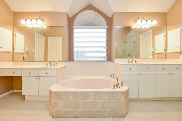 bathroom featuring a bath, a sink, a shower stall, two vanities, and tile patterned flooring