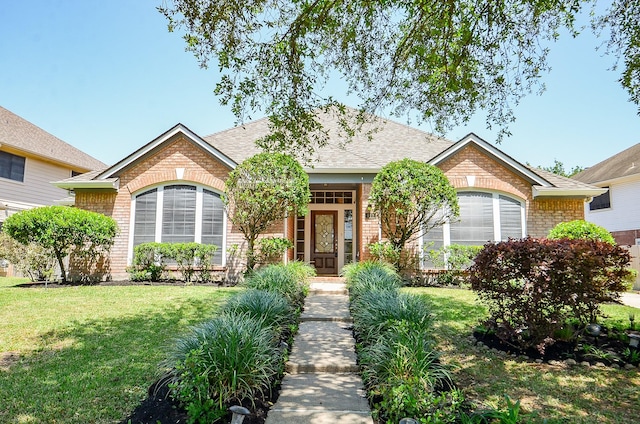 ranch-style house with roof with shingles, brick siding, and a front lawn
