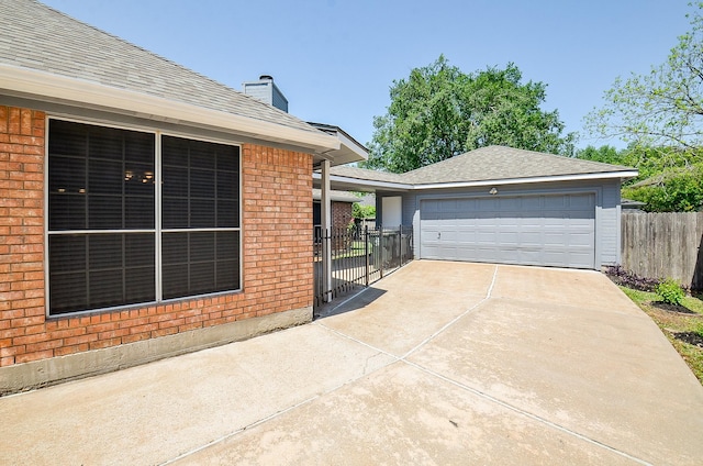 view of home's exterior featuring a shingled roof, brick siding, fence, and a chimney