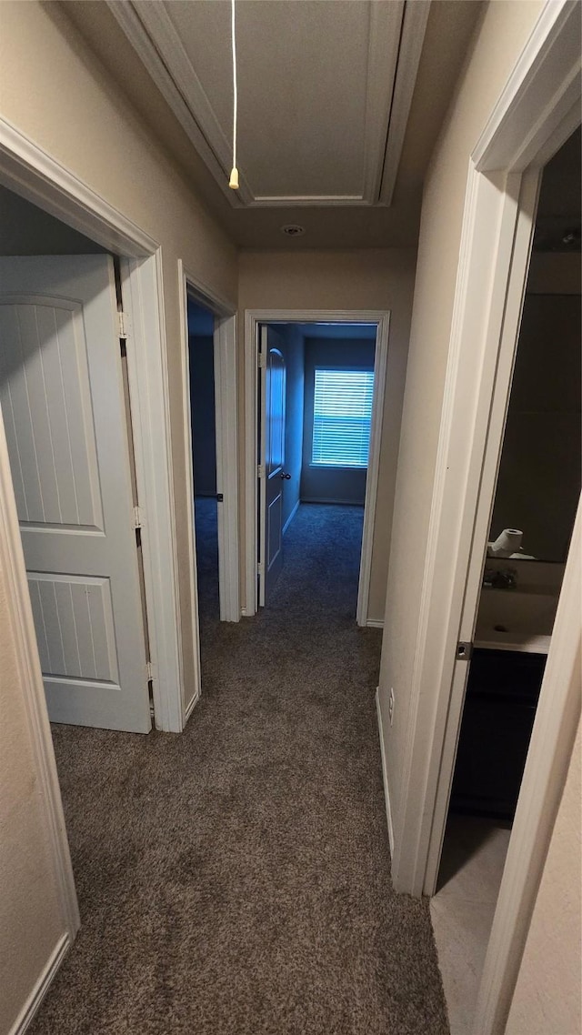 hall with attic access and dark colored carpet