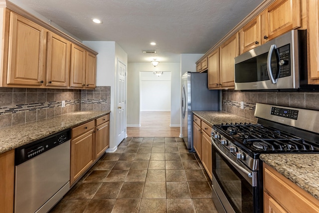23222 Drywood Crossing Ct, Spring, TX 77373 - kitchen featuring appliances with stainless steel finishes, baseboards, tasteful backsplash, light stone counters, and recessed lighting
