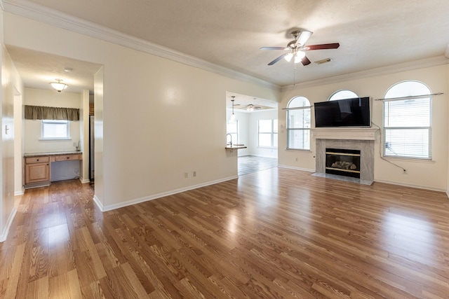 23222 Drywood Crossing Ct, Spring, TX 77373 - unfurnished living room featuring ceiling fan, wood finished floors, plenty of natural light, a premium fireplace, and ornamental molding