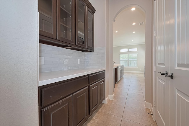 bar featuring decorative backsplash, light tile patterned flooring, baseboards, recessed lighting, and arched walkways