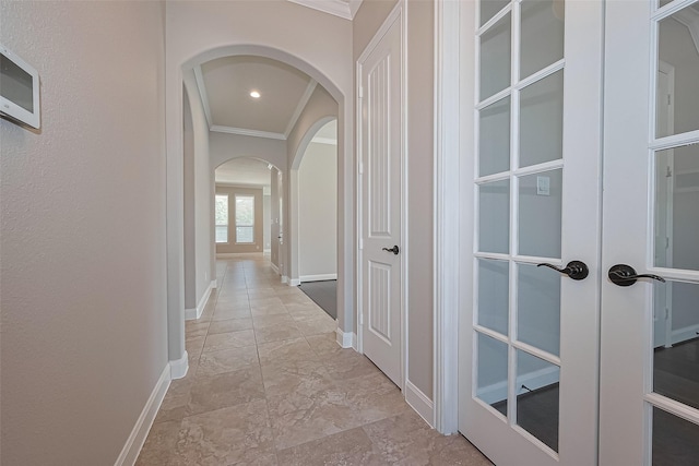 corridor featuring baseboards, arched walkways, and ornamental molding