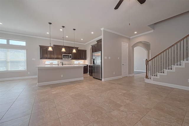 kitchen with light countertops, stainless steel appliances, arched walkways, and ornamental molding
