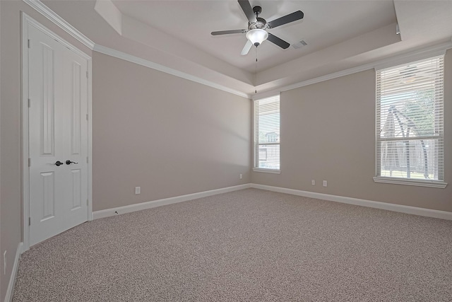 empty room featuring light colored carpet, a ceiling fan, a tray ceiling, and visible vents