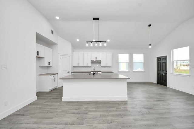 673 Rd 5822, Cleveland, TX 77327 - kitchen featuring high vaulted ceiling, under cabinet range hood, white cabinetry, an island with sink, and backsplash