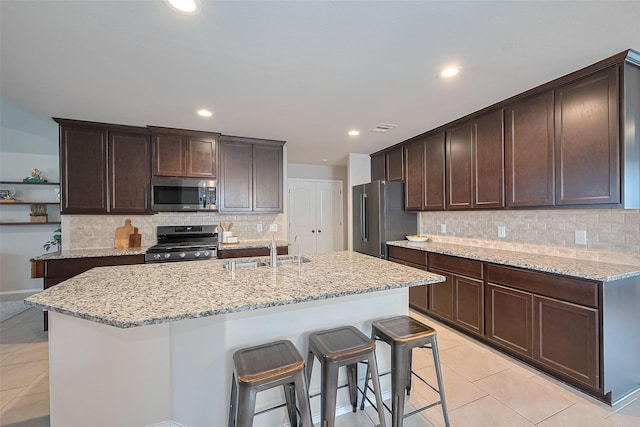 23806 Naples Shore Dr, Katy, TX 77493 - kitchen with light tile patterned floors, dark brown cabinets, light stone countertops, appliances with stainless steel finishes, and a sink