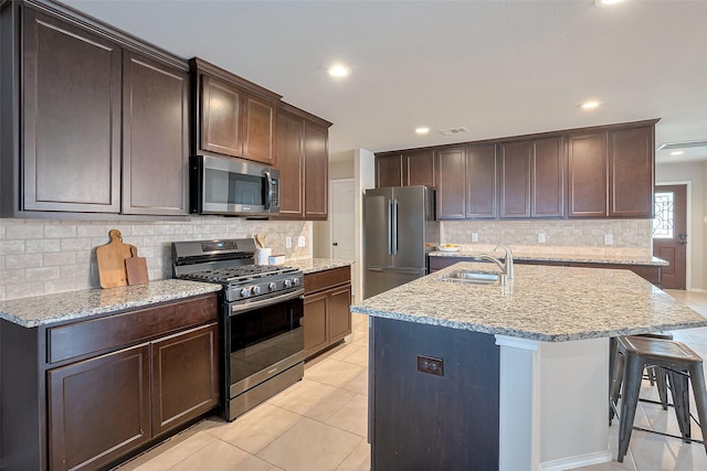 23806 Naples Shore Dr, Katy, TX 77493 - kitchen featuring visible vents, a sink, a center island with sink, light stone counters, and stainless steel appliances