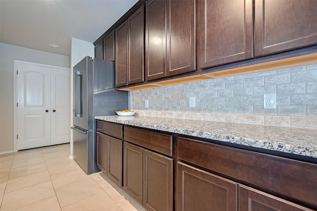 23806 Naples Shore Dr, Katy, TX 77493 - kitchen featuring dark brown cabinets, high quality fridge, light stone counters, light tile patterned flooring, and backsplash