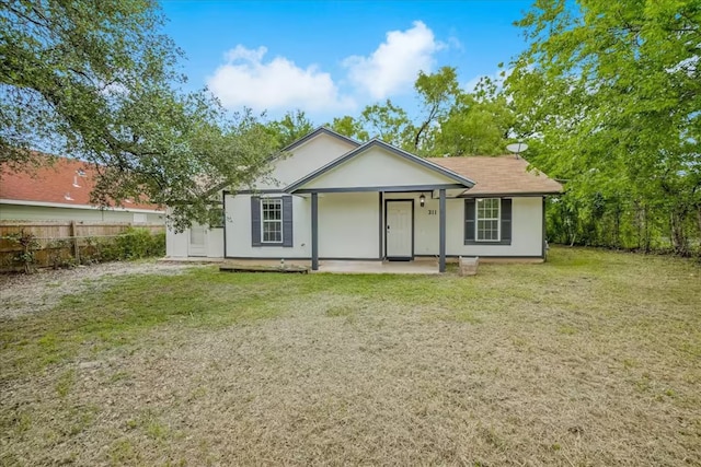 back of house with stucco siding, fence, and a lawn
