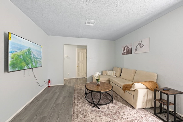 living area with visible vents, baseboards, wood finished floors, and a textured ceiling