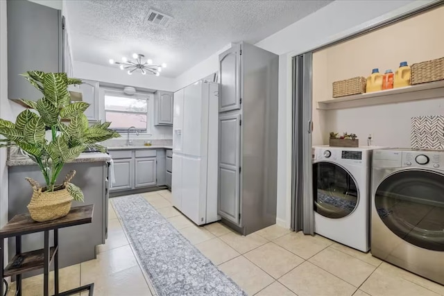 laundry room featuring visible vents, a sink, a chandelier, laundry area, and washing machine and dryer