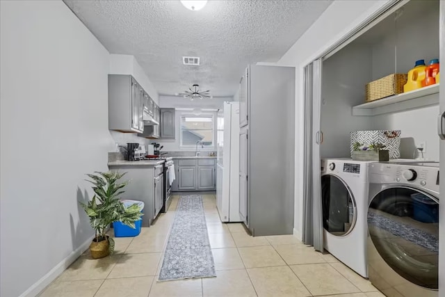 washroom with laundry area, light tile patterned floors, a textured ceiling, visible vents, and washer and clothes dryer