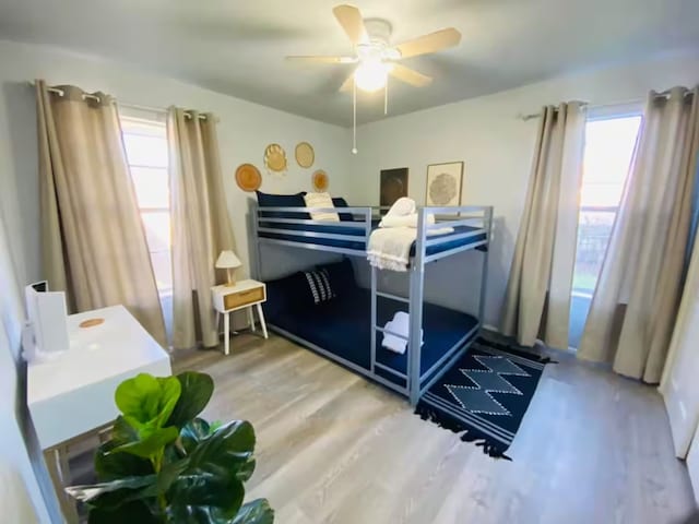 bedroom featuring wood finished floors, ceiling fan, and multiple windows