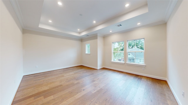 unfurnished room featuring baseboards, a raised ceiling, ornamental molding, recessed lighting, and light wood-style flooring
