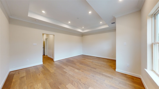 empty room featuring recessed lighting, light wood-style flooring, a tray ceiling, and baseboards
