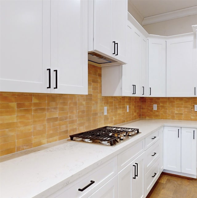 kitchen featuring tasteful backsplash, crown molding, and white cabinets