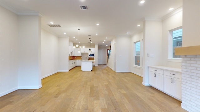 kitchen featuring white cabinets, light wood-style floors, visible vents, and ornamental molding