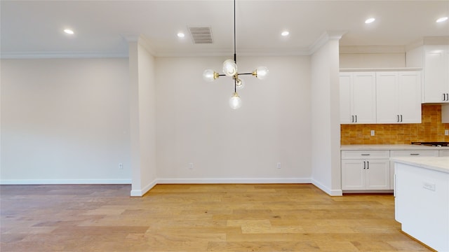 kitchen featuring light wood-style floors, ornamental molding, white cabinets, light countertops, and backsplash