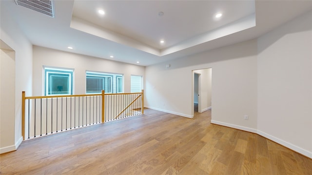 spare room with visible vents, baseboards, a tray ceiling, recessed lighting, and wood finished floors