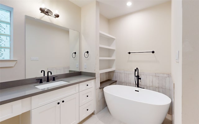 bathroom featuring a freestanding tub, vanity, recessed lighting, a wainscoted wall, and tile walls