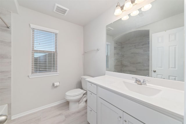 bathroom featuring visible vents, baseboards, toilet, vanity, and tiled shower