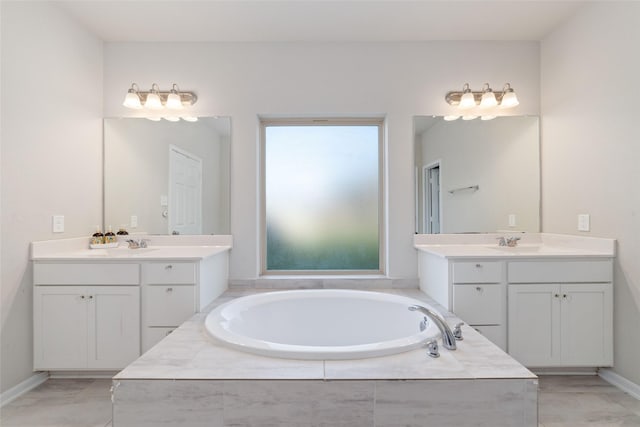 bathroom featuring two vanities, marble finish floor, a sink, and a garden tub