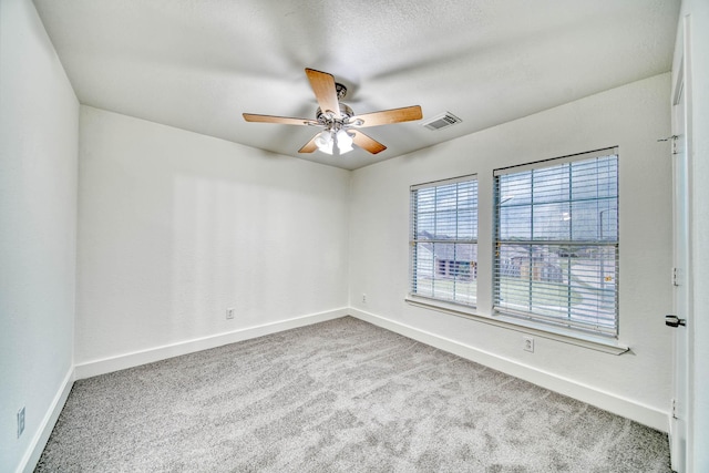 empty room with baseboards, visible vents, a ceiling fan, and carpet floors