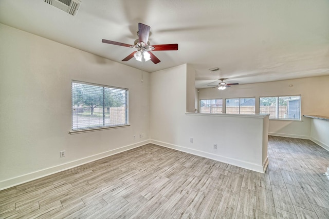 unfurnished room with a ceiling fan, visible vents, wood finished floors, and baseboards